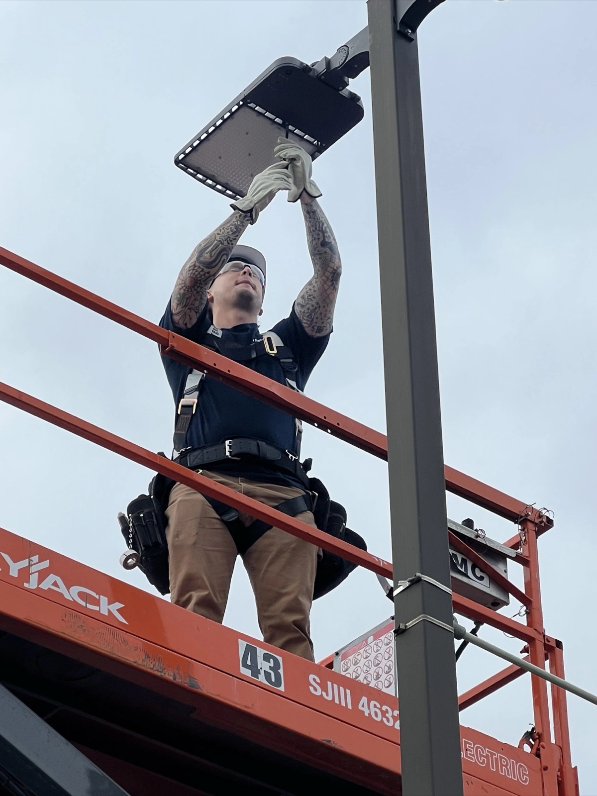 Soto Electric technician on a scissor lift installing a parking lot LED fixture