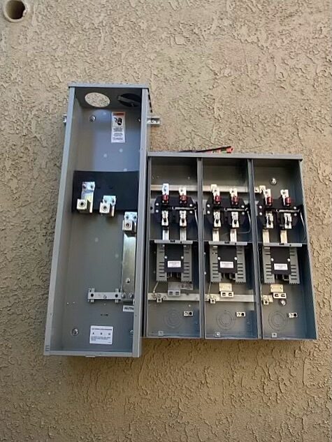 Open gutter and three empty meter sockets on a stucco wall